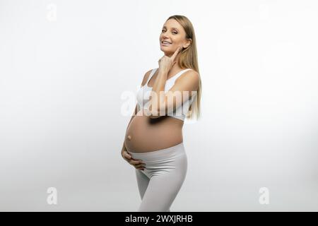 Bella donna bionda incinta che si sente felice e gioiosa Foto Stock