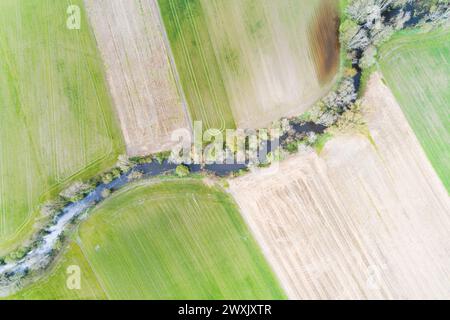 un fiume tra campi coltivati in primavera, vista droni zenithal Foto Stock