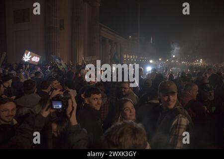 Berlino, dal 31 marzo al 1° aprile 2024 - in un'atmosfera carica di attesa e unità, la porta di Brandeburgo a Berlino emerse come punto focale di un significativo cambiamento sociale nella notte che portò alle prime ore del 1° aprile 2024. Questa storica occasione ha segnato il passo della Germania verso una nuova era nella politica sulle droghe con la parziale legalizzazione della cannabis per uso ricreativo, scatenando una celebrazione collettiva tra la folla riunita. La legge di riferimento, in vigore dal 1° aprile, consente agli adulti tedeschi di possedere e consumare legalmente cannabis, stabilendo limiti di possesso personale fino a 25 gr Foto Stock