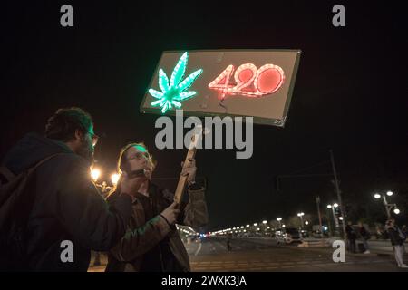 Berlino, dal 31 marzo al 1° aprile 2024 - in un'atmosfera carica di attesa e unità, la porta di Brandeburgo a Berlino emerse come punto focale di un significativo cambiamento sociale nella notte che portò alle prime ore del 1° aprile 2024. Questa storica occasione ha segnato il passo della Germania verso una nuova era nella politica sulle droghe con la parziale legalizzazione della cannabis per uso ricreativo, scatenando una celebrazione collettiva tra la folla riunita. La legge di riferimento, in vigore dal 1° aprile, consente agli adulti tedeschi di possedere e consumare legalmente cannabis, stabilendo limiti di possesso personale fino a 25 gr Foto Stock