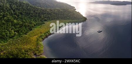 La fitta foresta pluviale copre la costa panoramica di Batanta meridionale, Raja Ampat. Questa regione biodiversificata è conosciuta come il cuore del Triangolo dei Coralli. Foto Stock