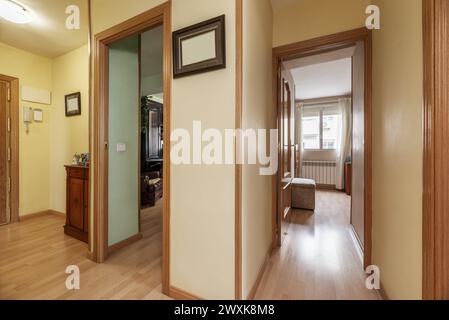 Corridoio del soggiorno di un appartamento con porte in quercia, pavimento in legno coordinato, credenza con specchio coordinato e pareti giallo pallido Foto Stock