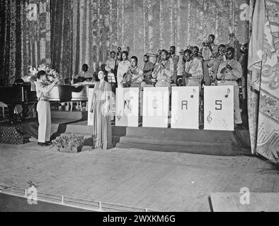 La signorina Josephine Baker, popolare interprete teatrale, canta l'inno nazionale come finale dello spettacolo tenuto al Teatro Municipale di Orano, Algeria, N. Africa. La band è diretta da T/Sgt. Frank W. Weiss CA. Maggio 1943 Foto Stock