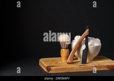 Apparecchiatura di rasatura classica con rasoio, spazzola e sapone su supporto in legno su sfondo scuro Foto Stock