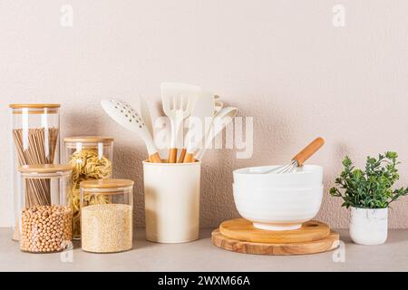 Splendido sfondo della cucina con area per conservare gli alimenti, cucchiai, utensili da cucina e piante verdi in una pentola. Vista frontale Foto Stock