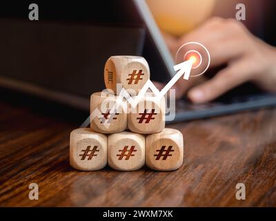 Il simbolo hashtag su un blocco di legno a forma di piramide con la freccia rivolta verso l'alto viene premuto sull'icona di destinazione quando un uomo d'affari lavora con un computer portatile. Affari Foto Stock