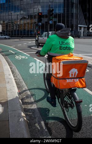 Corriere per consegne di cibo nella zona est di Londra. Il corriere del ciclo di consegna del cibo indossa marchi assortiti. Foto Stock