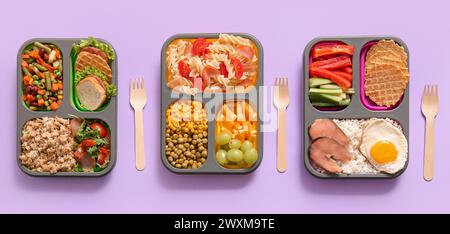 Cestini per il pranzo con diversi piatti gustosi su sfondo lilla Foto Stock