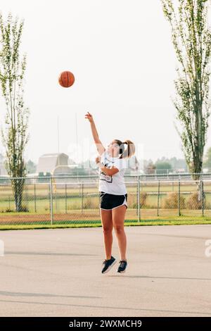 Adolescente caucasica che fa un colpo di basket Foto Stock