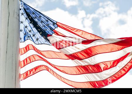 Bandiera americana retroilluminata sul palo che soffia nel vento Foto Stock