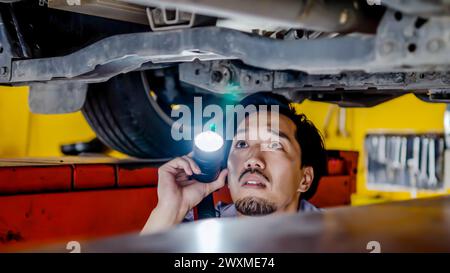 Un lavoratore maschio che ripara un'auto in un garage Foto Stock