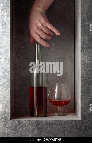 Sbraccio a mano per un decanter di brandy. Un'immagine concettuale sul tema delle bevande costose. Foto Stock