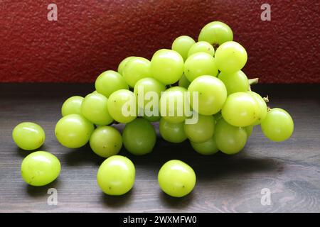 Mazzo di moscato fresco e maturo verde giallo brillante su tavola di legno Foto Stock