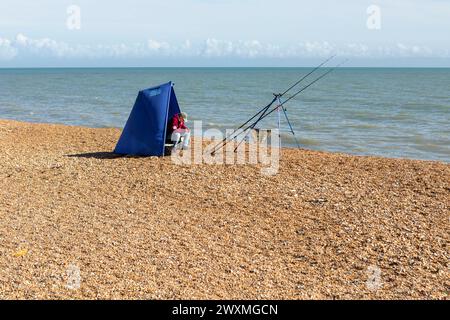 Un pescatore in una piccola pausa vento sulla spiaggia di ciottoli a Hythe, Kent, Regno Unito Foto Stock