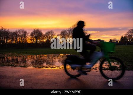 Un uomo guida una bicicletta a noleggio Lime mentre è al telefono Foto Stock