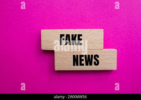 False notizie scritte su blocchi di legno con sfondo rosa. Simbolo concettuale. Copia spazio. Foto Stock