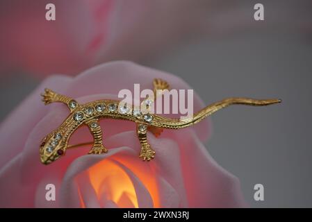 Una piccola spilla di lucertola arroccata su una candela rosa illuminata Foto Stock