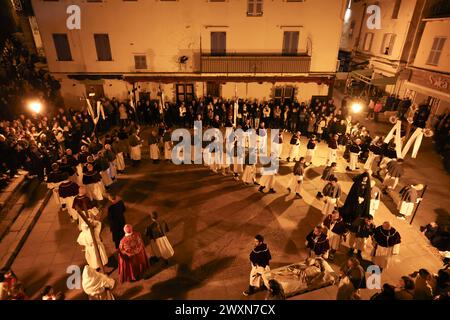 La tradizionale processione "Granitula" per le vie di Calvi, Corsica, il venerdì Santo. Questa giornata commemora la passione di Cristo con pochi penitenti, e a Calvi si svolge una particolare processione. Si parte dalla cattedrale di Saint Jean-Baptiste, nella cittadella, per andare alla chiesa di Sainte Marie Majeure, nella città bassa. Sulla piazza della chiesa i confratelli di San Anthony e St. Erasmus gira a lungo per stringere e formare una lumaca prima di allargare il cerchio e lasciare le altre stazioni. A piedi nudi, il penitente che porta la croce pesante per riprodurre il Calvario di Cristo che porta la sua croce. Calvi, Cor Foto Stock