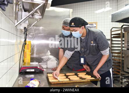 (240401) -- SHENZHEN, 1° aprile 2024 (Xinhua) -- i giovani autistici Liu Hanyang (R) e Peng Jingrui, fanno la pasticceria in un panificio a Shenzhen, nella provincia del Guangdong della Cina meridionale, 21 marzo 2024. Liu Hanyang, 25 anni, e Peng Jingrui, 23 anni, lavorano come panettiere alla panetteria dal giugno 2023. Oltre a preparare pane e spuntini con il loro insegnante, possono anche lavorare come cassieri e fattorini. Questo martedì segna la diciassettesima giornata mondiale della consapevolezza dell'autismo. Nella Shenzhen del sud della Cina, alcuni giovani autistici, chiamati "figli delle stelle", si sono integrati nella società e stanno inseguendo i loro sogni. Nell'ultimo anno Foto Stock