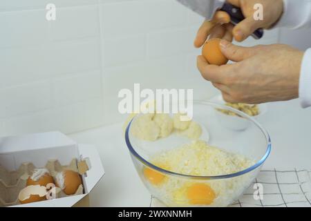 Un uomo sta su una ciotola di cavolfiore tritato, rompendo le uova e tenendo un coltello in concentrazione. Foto Stock