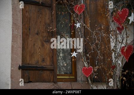 Antiche persiane in legno con cuori festivi fatti a mano e decorazioni a stelle a Kaysersberg-Vignoble, Alsazia, Francia. Foto Stock