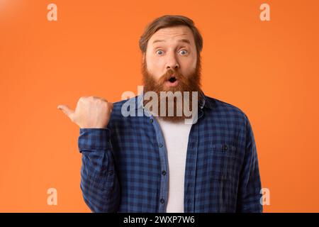 Un uomo dalla barba dai capelli rossi che punta da parte con il pollice, studio Foto Stock