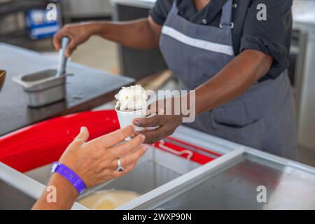 Vista ravvicinata di un lavoratore del ristorante che consegna una tazza di gelato a un turista. Curacao. Foto Stock