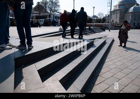 Istanbul, Turchia - 23 marzo 2024: Le persone stanno camminando su una rampa e scale architettoniche moderne in Piazza Uskudar. Un fiorista sta sta cercando di vendere rose. Foto Stock