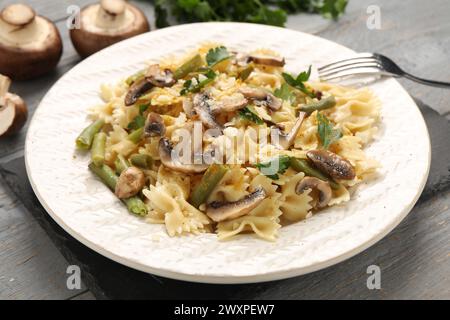 Pasta vegetariana con funghi, prezzemolo, fagioli e formaggio su un tavolo di legno grigio, primo piano Foto Stock
