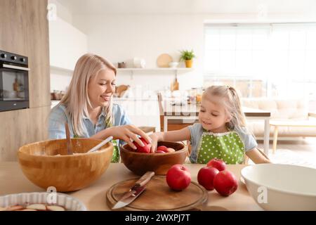 Madre felice con la sua piccola figlia che cucina la torta di mele in cucina Foto Stock