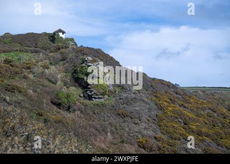 Vista della capanna all'hotel gara Rock, che sorge in alto sulla scogliera, accanto al sentiero costiero SW sotto il cielo blu con grandi nuvole bianche Foto Stock