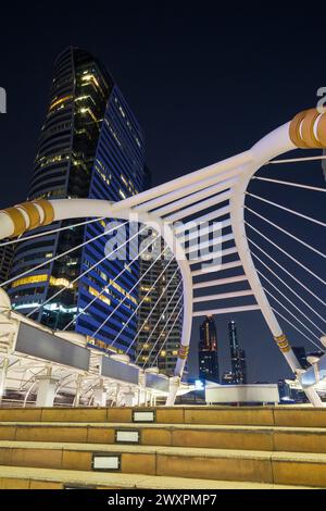 Chong Nonsi Skywalk - passerella pedonale illuminata, arco del ponte - e grattacieli nel centro di Bangkok, Thailandia, al crepuscolo. Foto Stock