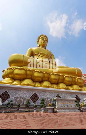 Vista dall'angolo basso della grande, alta e dorata statua del Buddha al Tempio Phasi Charoen di Wat Paknam (Pak Nam) a Bangkok, Thailandia, in una giornata di sole. Foto Stock