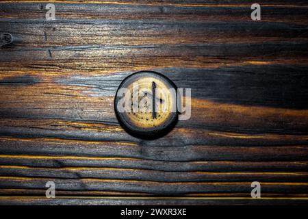Rune Naudiz scolpita in legno su fondo in legno - Elder Futhark Foto Stock