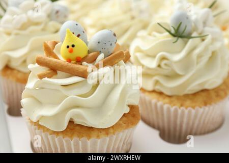 Gustosi cupcake pasquali con panna alla vaniglia in scatola, primo piano Foto Stock