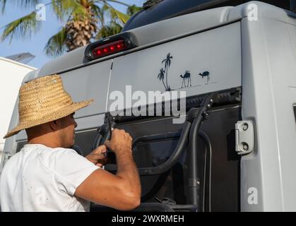 Tiznit, Marocco - 18 marzo 2024: Artista marocchino che dipinge arte decorativa su un camper nel centro di Tiznit Foto Stock