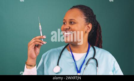 Il giovane e amichevole medico nero regge la siringa dell'ago di iniezione, schizza la medicina Foto Stock