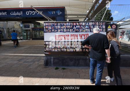 Una coppia che guarda un poster con le foto degli ostaggi israeliani a Gaza. Park Hamesila, Tel Aviv, Israele. Foto Stock