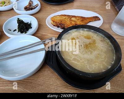 Hwangtae gukbap, o zuppa di riso al pollack essiccato, famosa in Corea come piatto haejang (sbornia), servito con platorello alla griglia e altri contorni Foto Stock