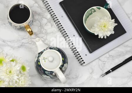 Caffè, fiori bianchi, taccuino, penna su un tavolo, piano. Foto Stock