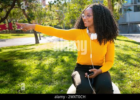 Donna afroamericana che punta il pollice da un lato Foto Stock