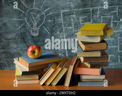 Pile di libri di fronte alla lavagna nera e alla mela rossa.ritorno a scuola, l'istruzione è potere, ricerca, concetto di apprendimento, spazio di copia gratuito Foto Stock