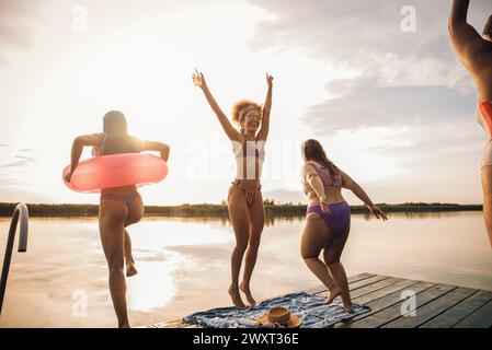 Gruppo di amiche che si godono una giornata d'estate saltando al lago. Foto Stock