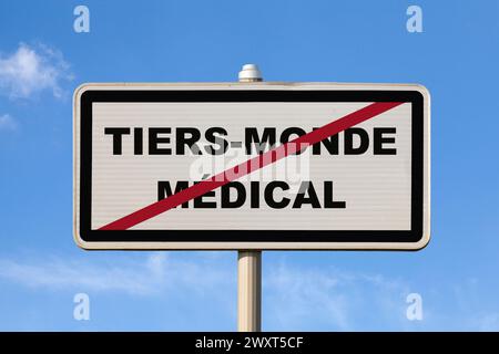 Un cartello francese di uscita della città contro un cielo blu con scritto al centro in francese "Tiers-monde médical", che in inglese significa "terzo mondo medico". Questo Foto Stock