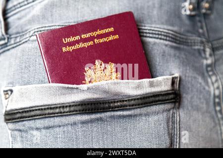 Primo piano su un passaporto francese nella tasca posteriore di jean. Foto Stock