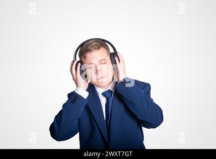 Giovane e carino ragazzo con le cuffie a occhi chiusi Foto Stock