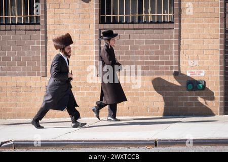 Su Purim, 2 uomini chassidici gettarono un'ombra gigante sulla strada per i servizi mattutini. Su Wythe Ave a Williamsburg, Brooklyn, New York. Foto Stock