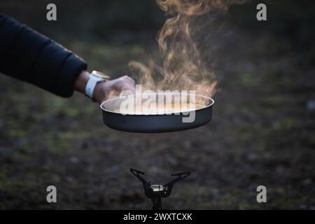 Cucinare all'aperto in campeggio usando il gas. Uova strapazzate in una padella. Primo piano. Foto Stock