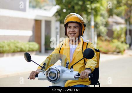 Ritratto del corriere in uniforme gialla in moto Foto Stock