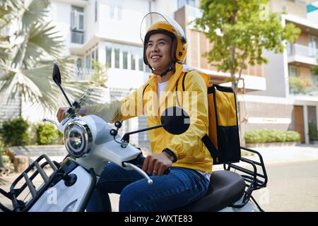 Corriere sorridente in moto con casco Foto Stock